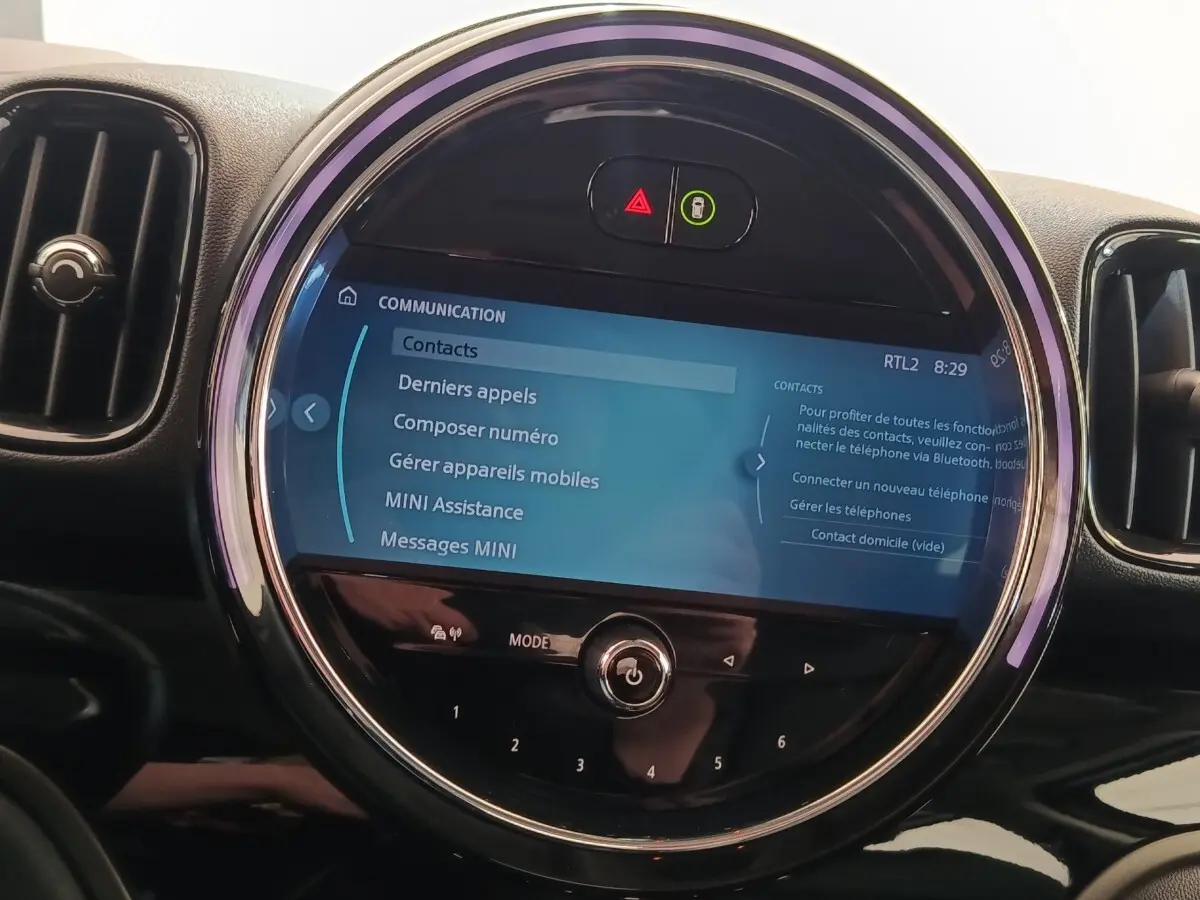 Gros plan sur l’écran tactile central rond du tableau de bord du MINI Countryman noir, affichant le menu communication.