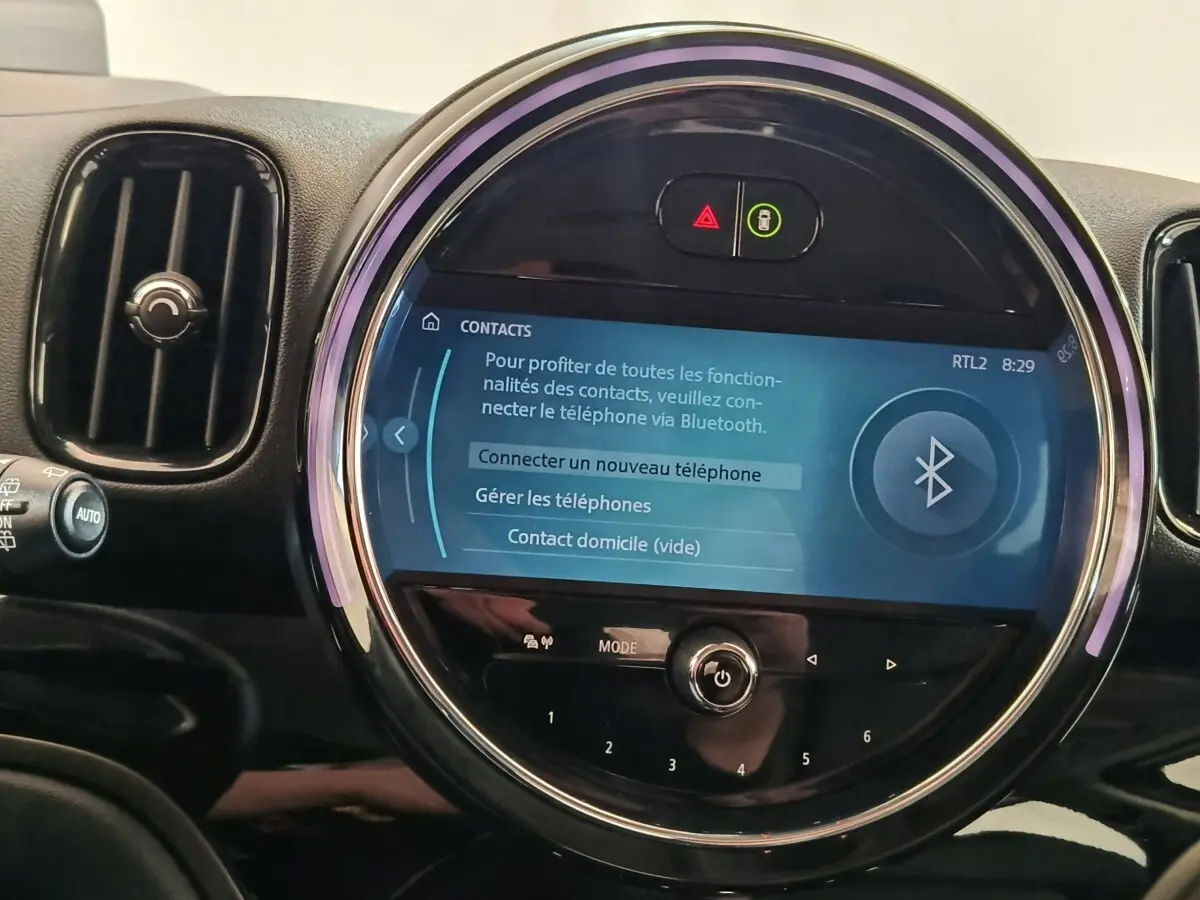 Gros plan sur l’écran tactile central rond du tableau de bord du MINI Countryman noir, affichant la connexion Bluetooth.