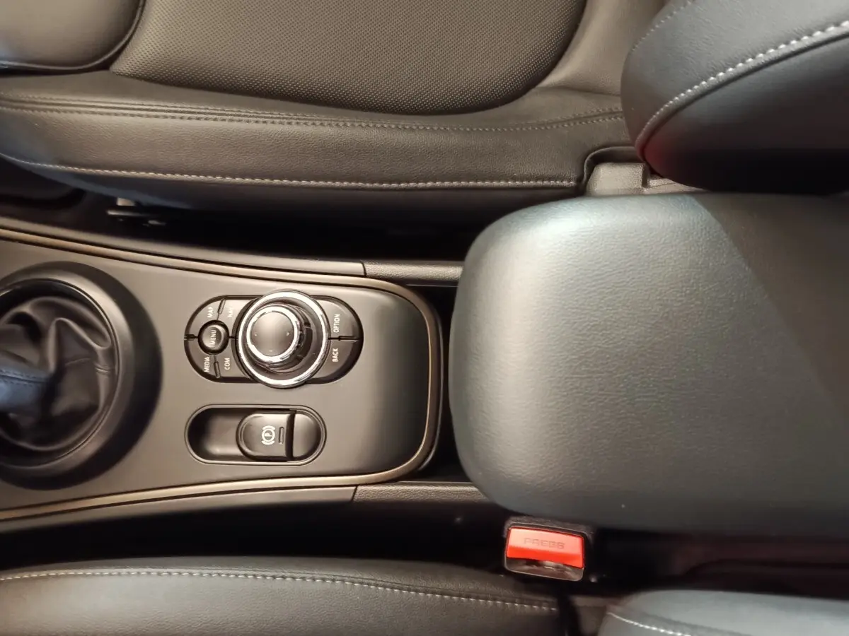 Vue rapprochée de la console centrale noire du MINI Countryman 2023, avec commandes et accoudoir en cuir.