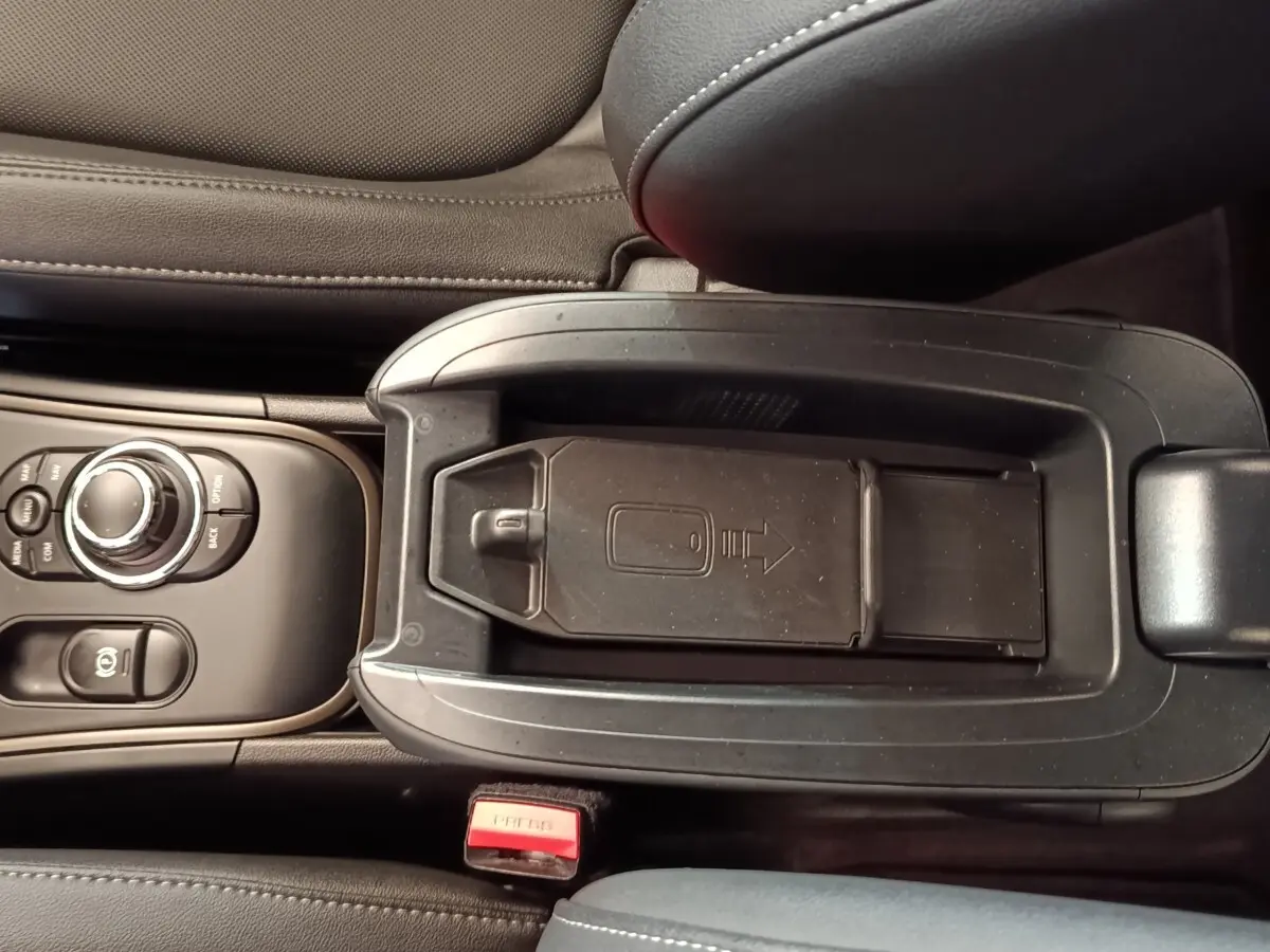 Vue plongeante sur la console centrale noire du MINI Countryman Cooper SE avec rangement réfrigéré et commandes circulaires.