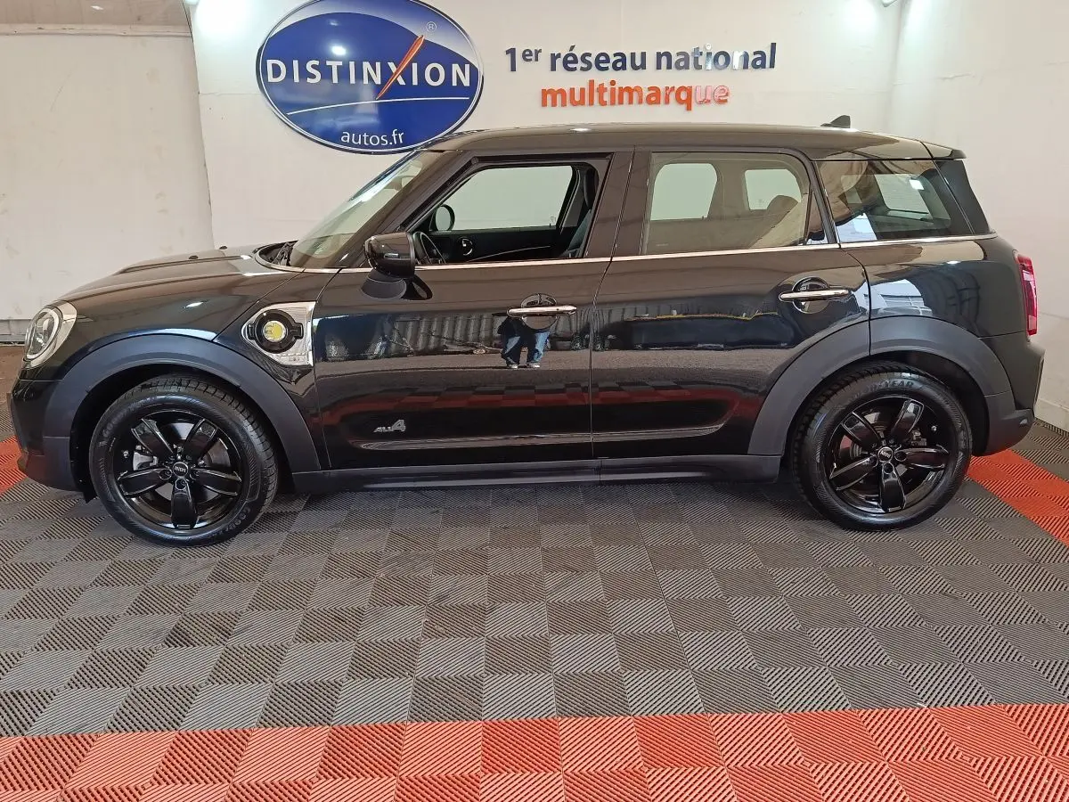 Vue de profil côté gauche d'une MINI Countryman Cooper SE noire avec jantes noires et badge hybride visible.