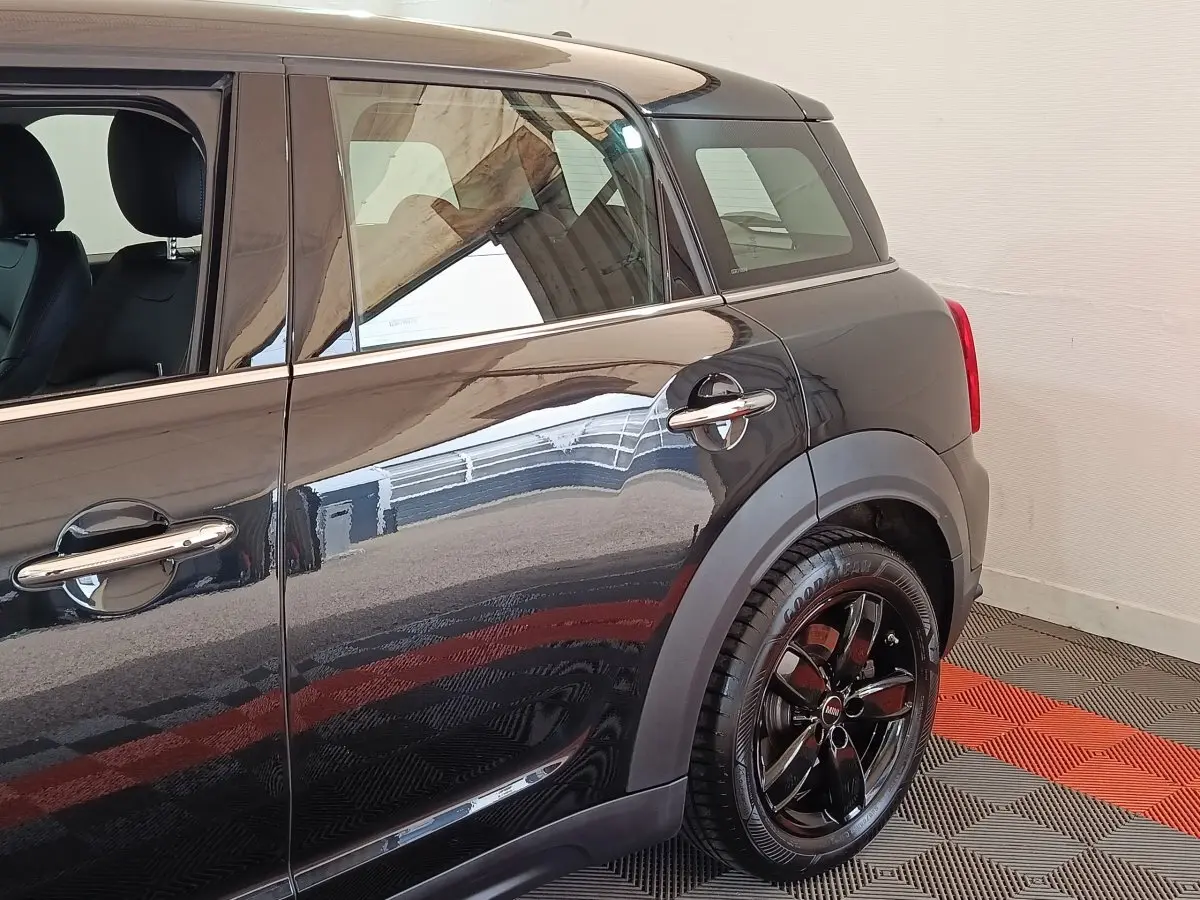 Vue latérale droite du MINI Countryman Cooper SE noir, mettant en valeur la roue arrière et les poignées chromées.
