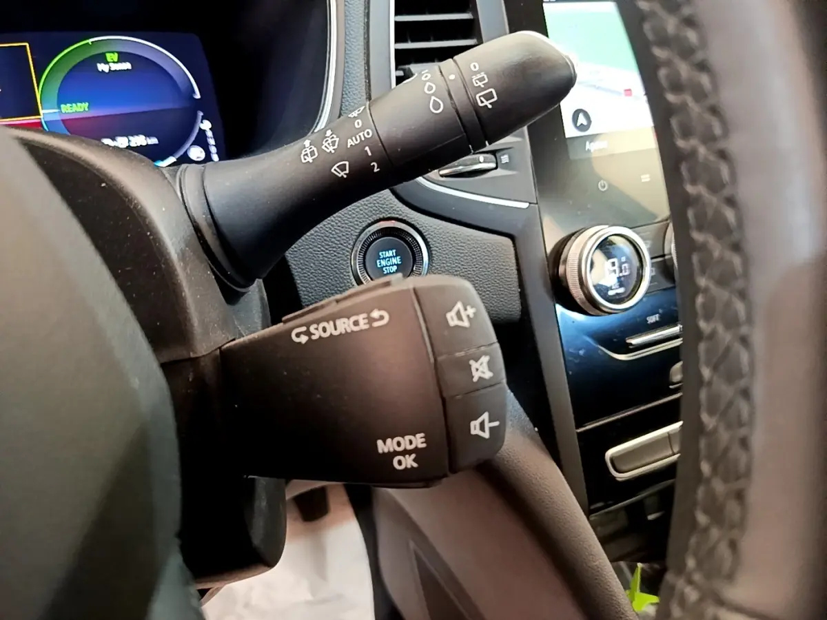 Gros plan sur la commande au volant et le tableau de bord digital de la Renault Mégane Business E-Tech hybride blanche, intérieur avant.