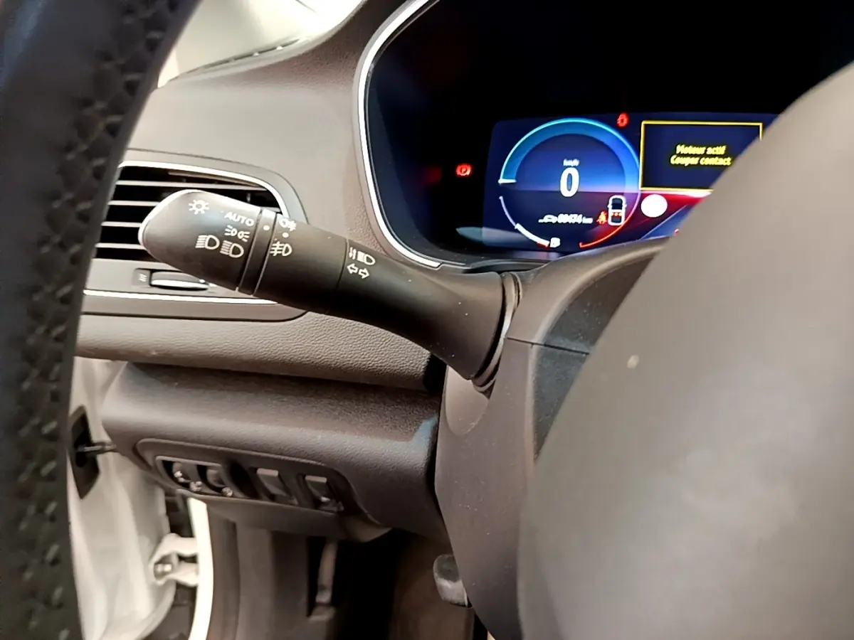 Vue rapprochée du combiné d'instruments digital et commande des phares à gauche sur Renault Mégane Business E-Tech hybride blanc.