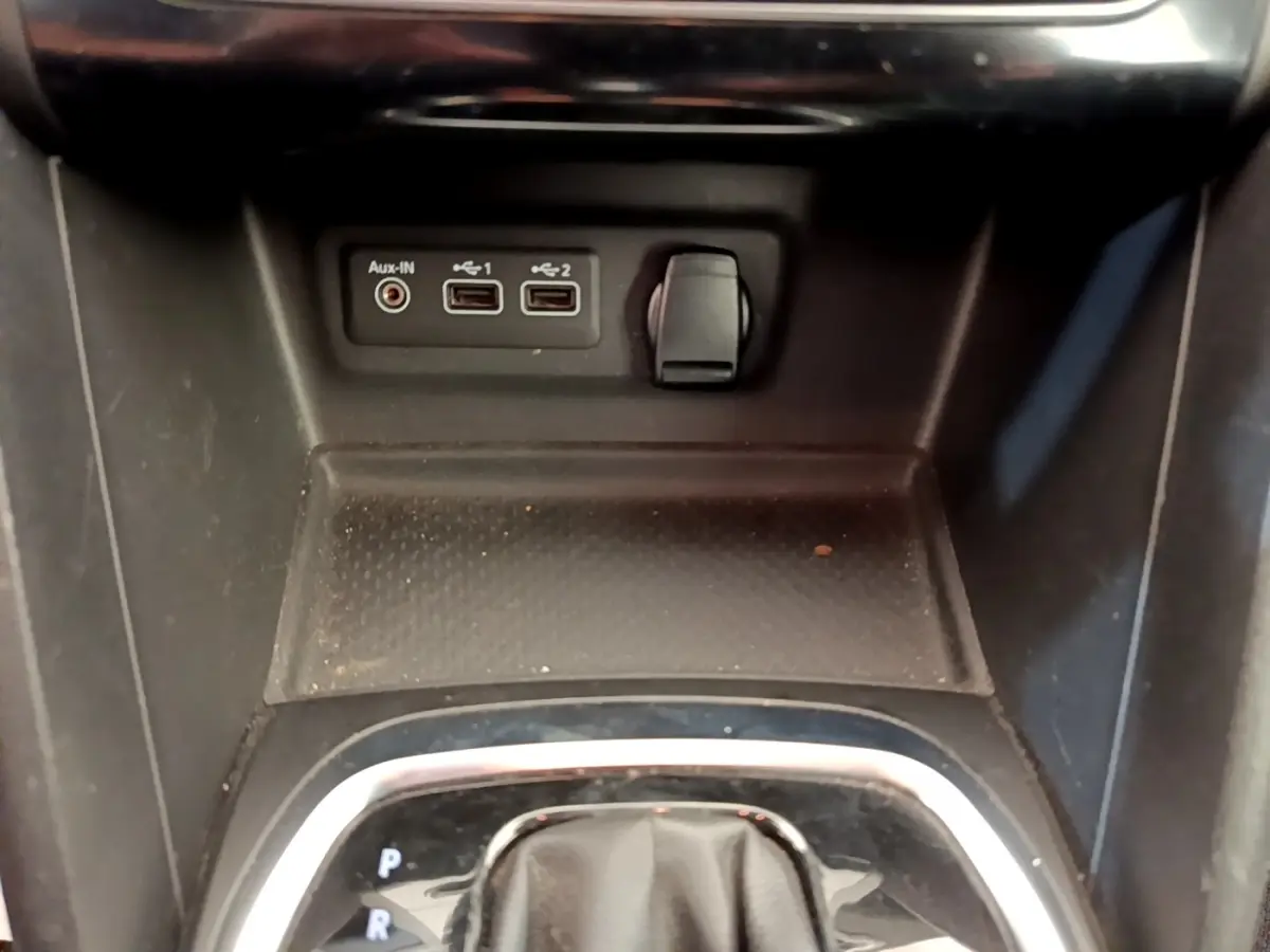 Gros plan sur la console centrale noire de la Renault Mégane Business E-Tech hybride, avec ports USB et prise auxiliaire.