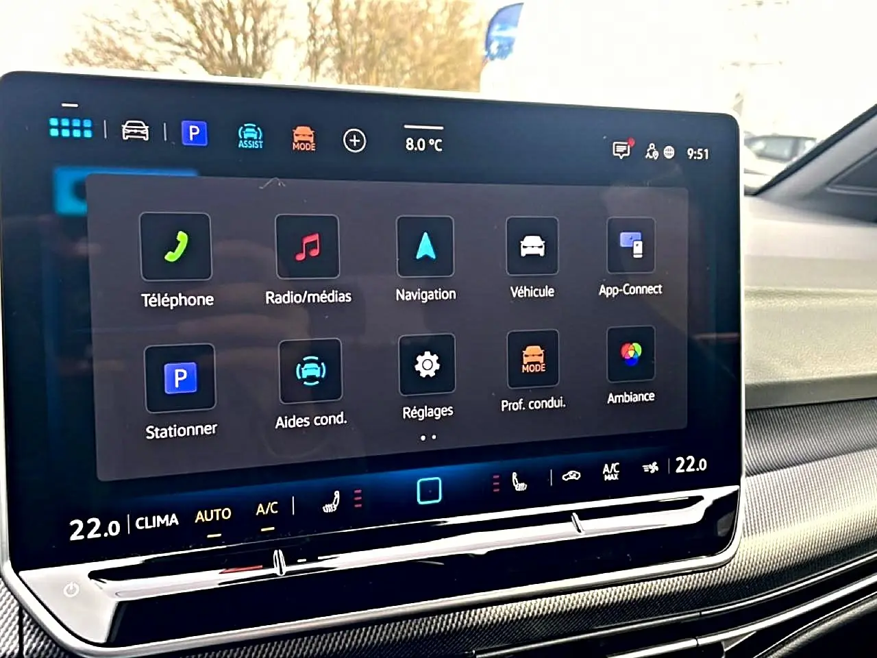 Écran tactile central affichant les menus de navigation et médias dans une Volkswagen Golf noire, vue intérieure.