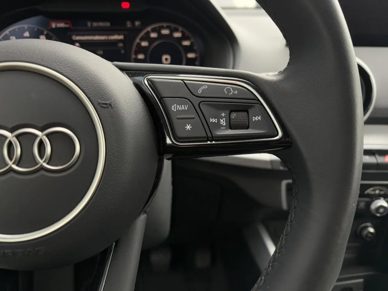 Gros plan sur le volant cuir noir multifonction de l'Audi Q2 30 TFSI 110 S-Line 2024 avec commandes audio visibles