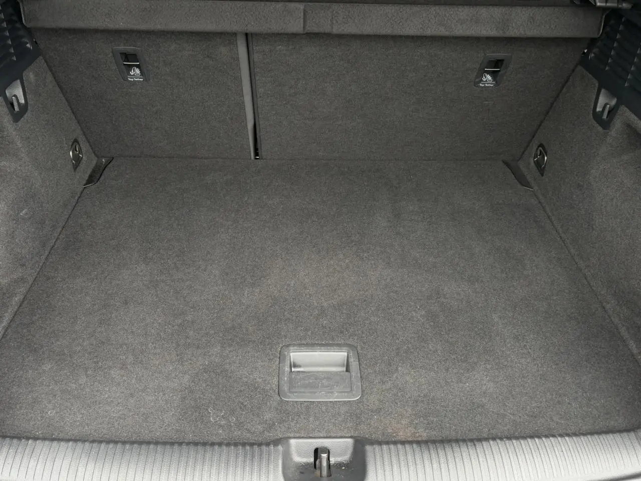 Coffre spacieux et vide de l'Audi Q2 30 TFSI 110 S-Line 2024, vue plongeante sur la moquette grise.
