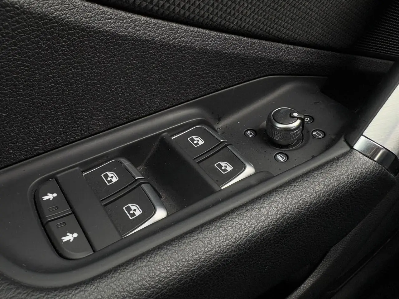 Gros plan sur les commandes de lève-vitres et réglage des rétroviseurs côté conducteur d'Audi Q2 30 TFSI blanc Glacier.