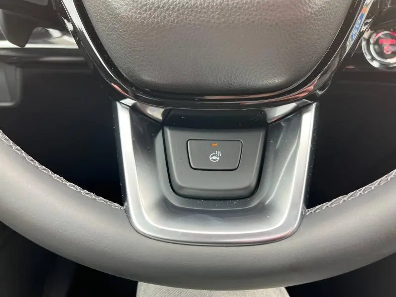 Bouton de chauffage du volant sur le cuir noir du volant du Honda CR-V 2024 blanc nacré, vue rapprochée centrale.