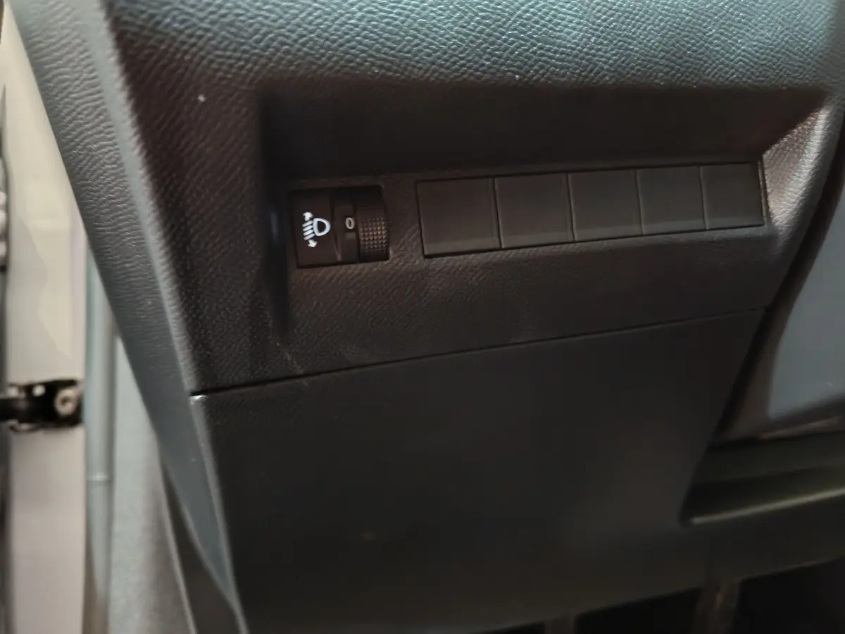 Détail du tableau de bord côté gauche en plastique noir mat sur Peugeot 208 gris clair 2025 PureTech Allure