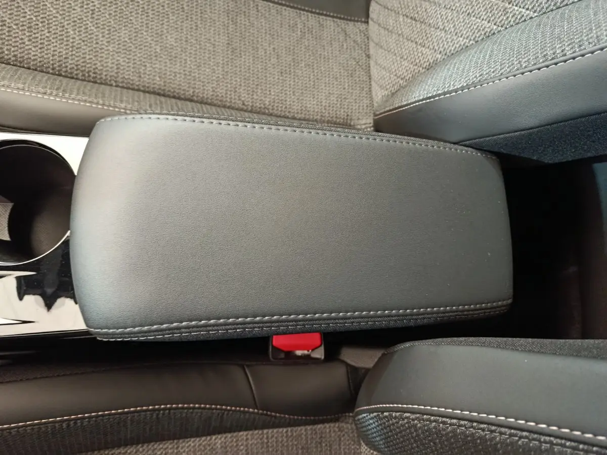 Vue rapprochée de l'accoudoir central en cuir noir avec surpiqûres blanches dans l'habitacle gris du Peugeot 208 2025.