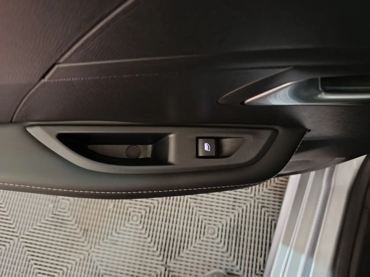 Poignée intérieure côté gauche de porte avant gris clair de la Peugeot 208 PureTech 100 S&S Allure 2025 avec bouton de verrouillage.