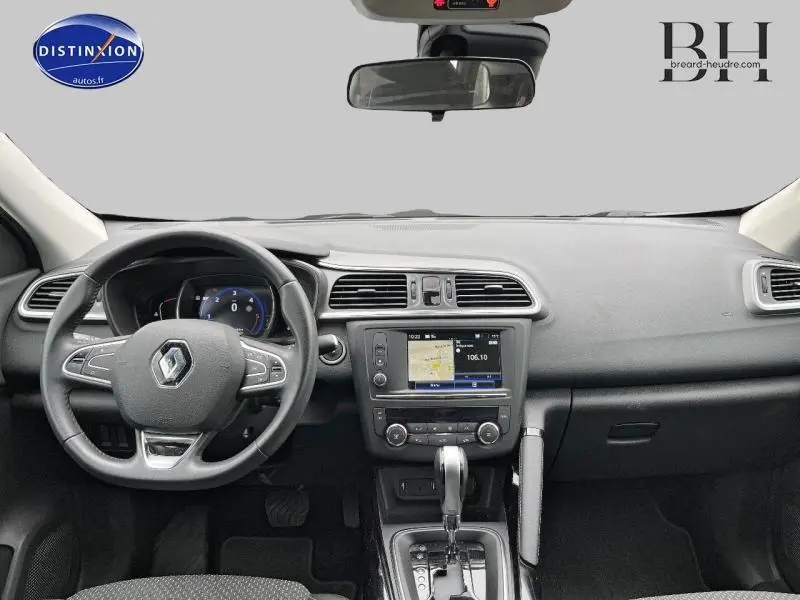 Vue intérieure frontale du tableau de bord du Renault Kadjar gris, avec volant cuir multifonction et écran tactile GPS.