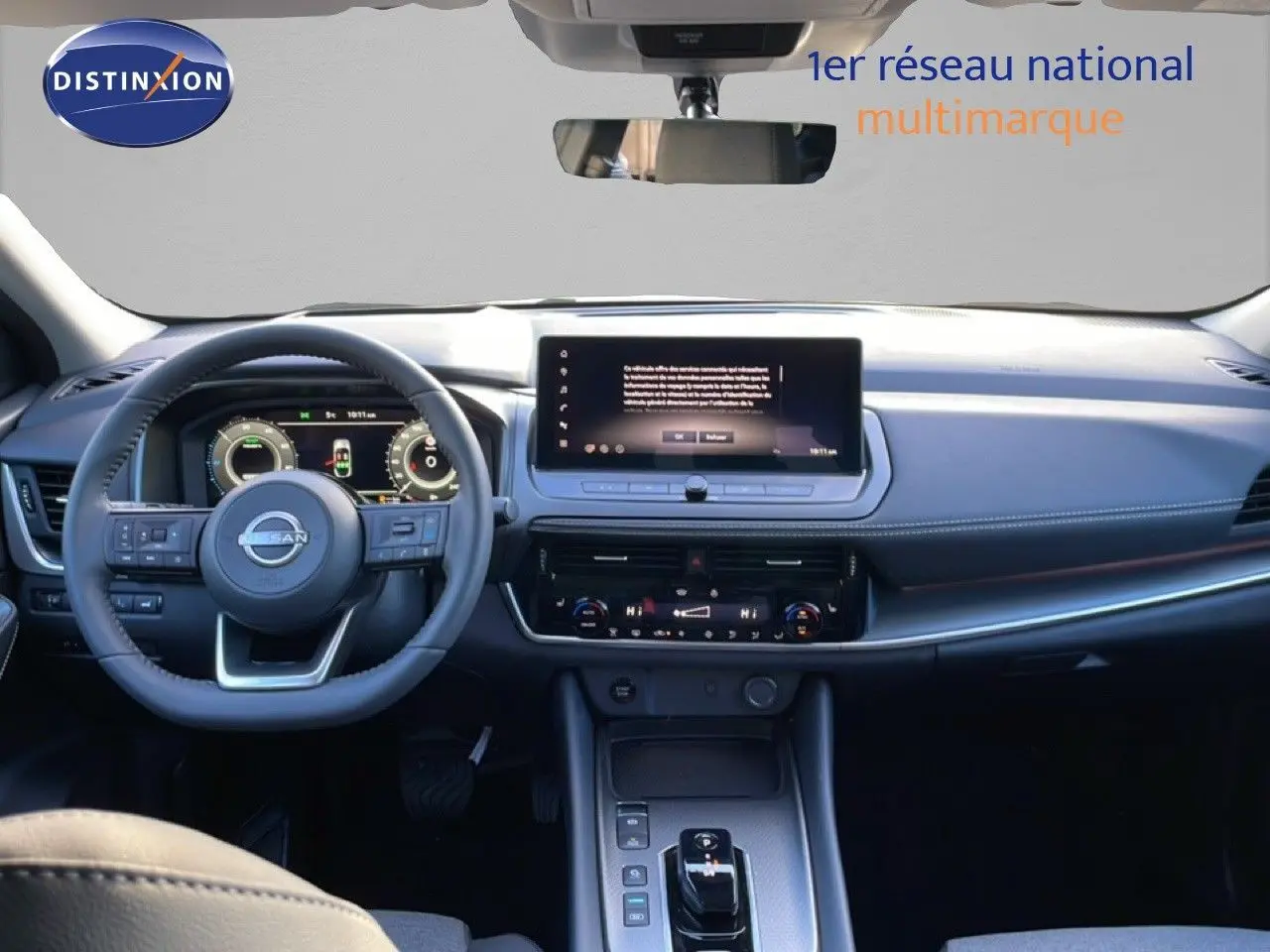 Vue intérieure frontale du tableau de bord du Nissan Qashqai gris argile, avec écran tactile et volant multifonction.