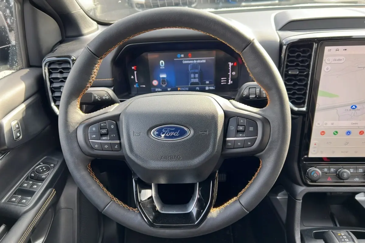 Vue rapprochée du volant cuir noir avec surpiqûres marron et tableau de bord numérique du Ford Ranger Wildtrak 2025.