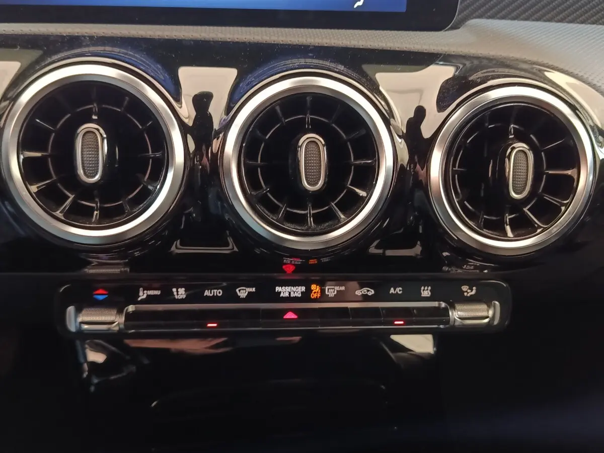 Détail du tableau de bord de la Mercedes Classe A 250 e Business Line 2023, montrant les aérateurs ronds et commandes climatisation.