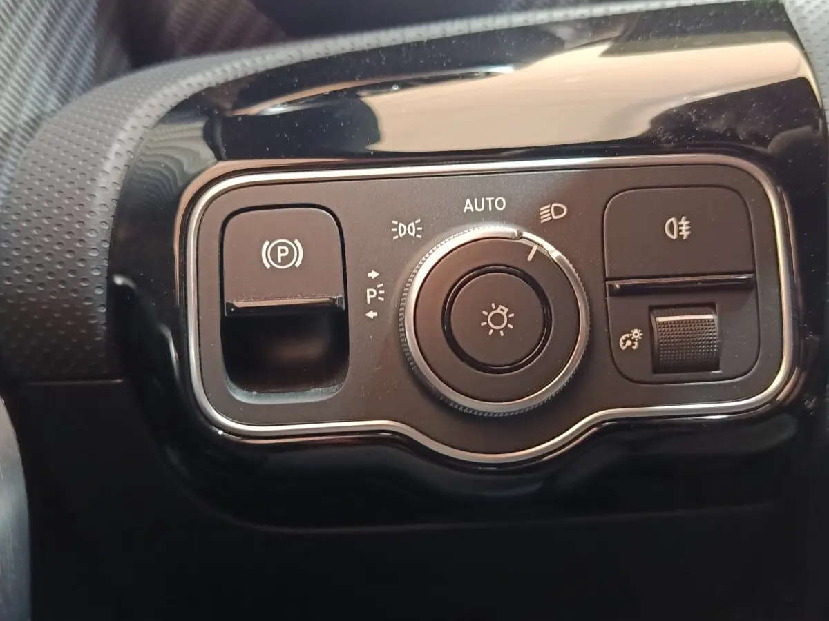 Gros plan sur le panneau de commande des phares et du frein à main électrique dans un Mercedes Classe A gris clair 2023.
