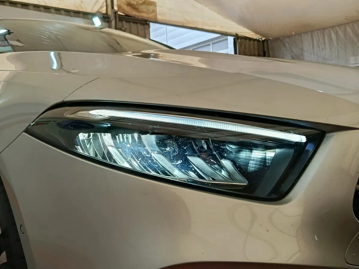 Gros plan sur le phare avant droit gris clair d'une Mercedes Classe A 250 e Business Line 2023 avec LED distinctive.