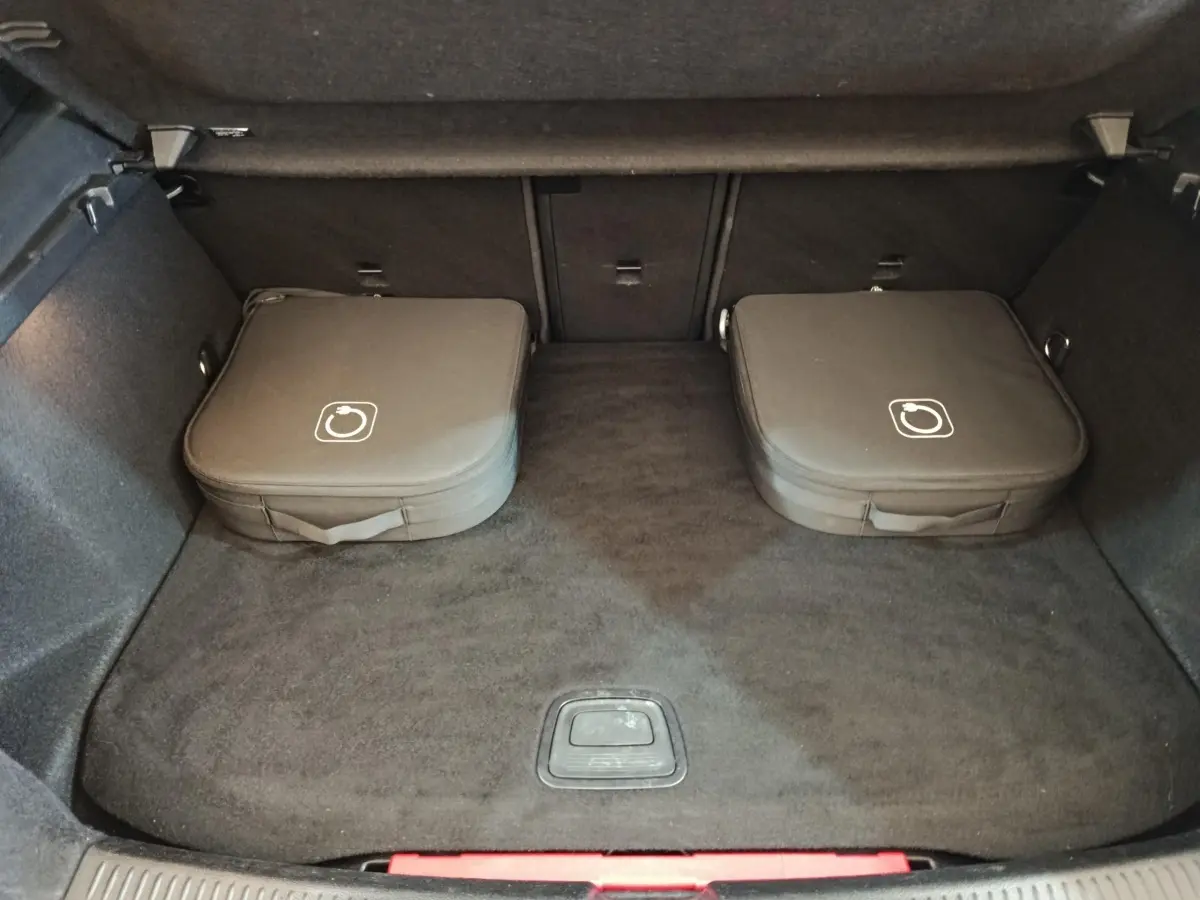 Coffre ouvert d’une Mercedes Classe A 250 e Business Line 2023, avec deux sacs de chargeurs hybrides gris foncé posés au fond.