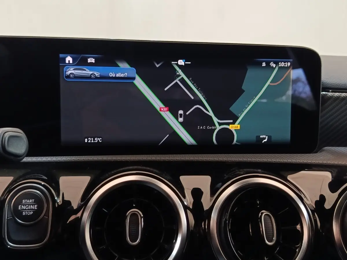 Vue rapprochée de l’écran tactile central et des aérateurs ronds chromés du tableau de bord noir brillant d’une Mercedes Classe A 250 e.
