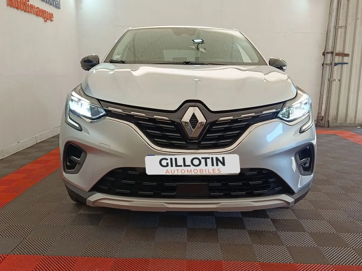 Vue frontale d'un Renault Captur gris clair avec phares LED allumés et calandre noire distinctive.