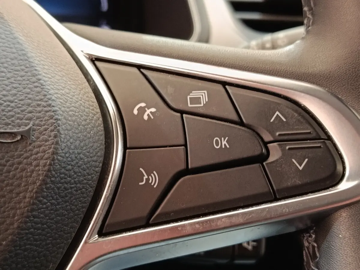 Gros plan sur les commandes multifonctions noires du volant cuir synthétique du Renault Captur gris clair, version Intens E-TECH 2021.