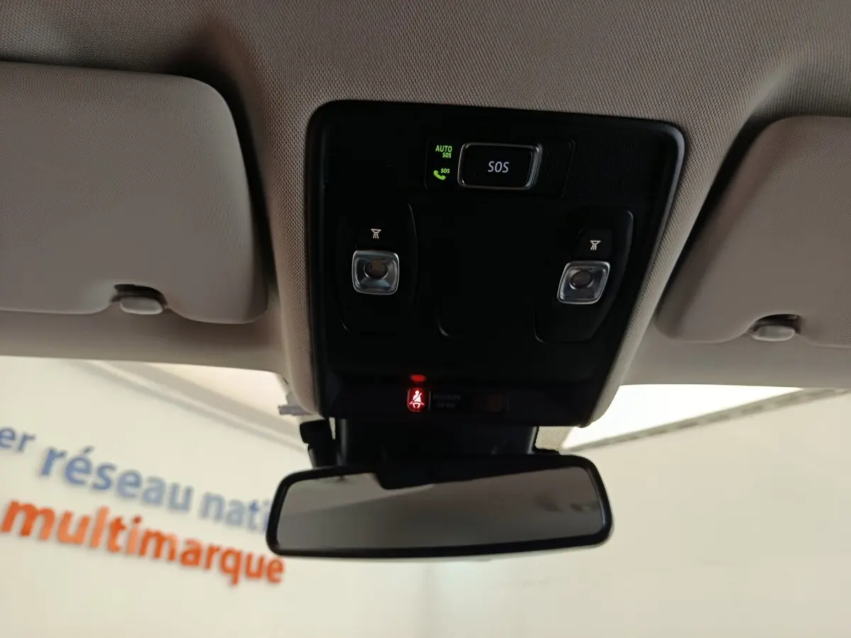 Vue intérieure centrée sur le plafonnier avec boutons SOS et éclairage, rétroviseur intérieur et ciel de toit beige.