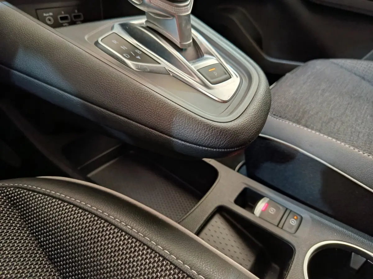Gros plan intérieur sur la console centrale et levier de vitesse automatique du Renault Captur Intens E-TECH gris clair.