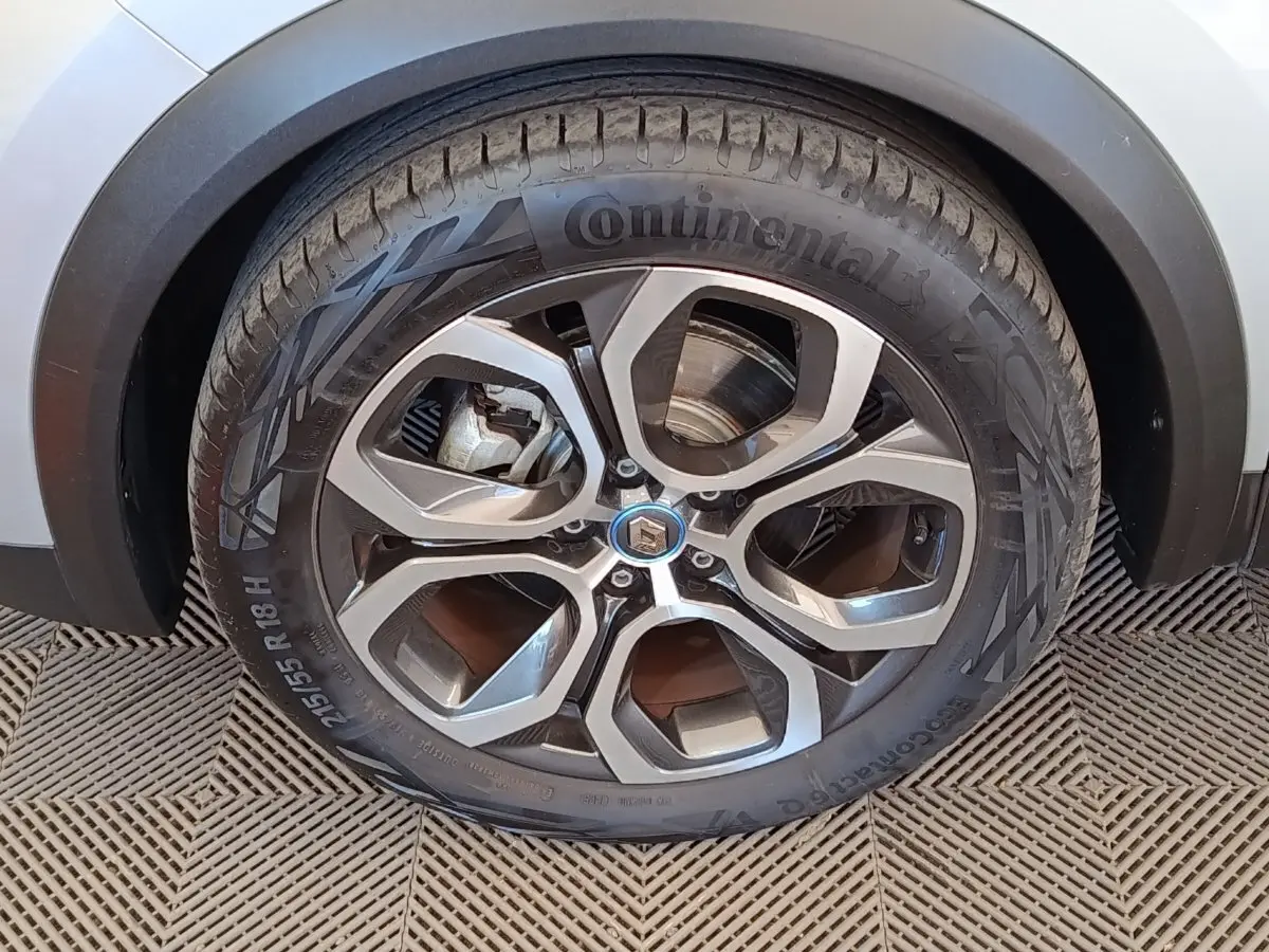 Gros plan sur la roue arrière droite d’un Renault Captur gris clair, avec passage de roue noir et sol en damier.