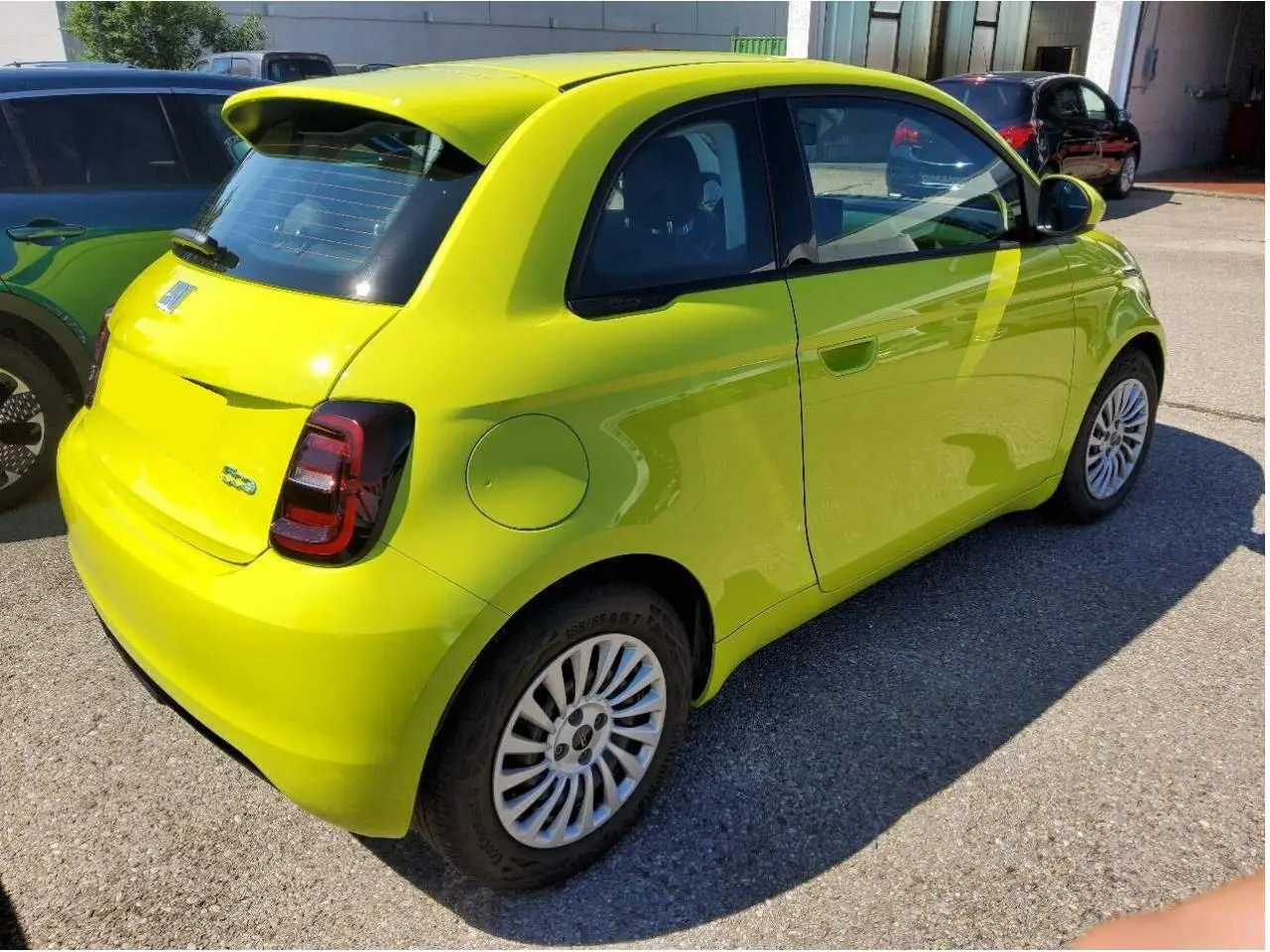 Fiat 500 électrique jaune Acid vue 3/4 arrière côté droit, avec feux arrière foncés et jantes multibranches.