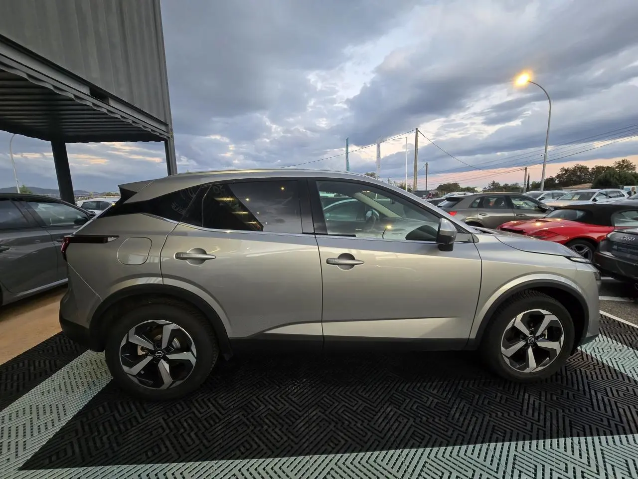 Nissan Qashqai III gris silver vu de profil côté gauche, avec jantes alliage 18 pouces et vitres teintées arrière.