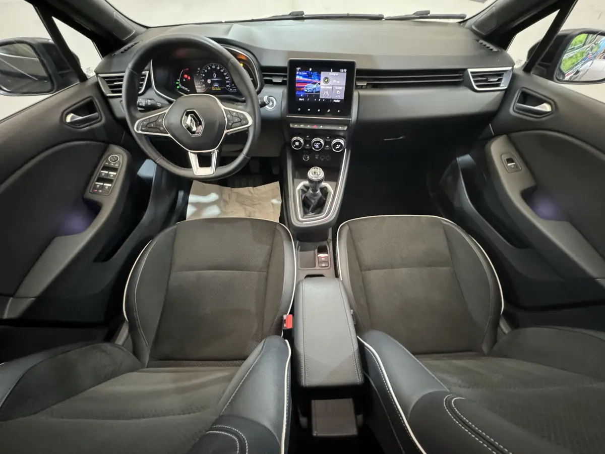 Vue intérieure avant de la Renault Clio Intens TCe 100 noire, avec tableau de bord moderne et écran tactile central.