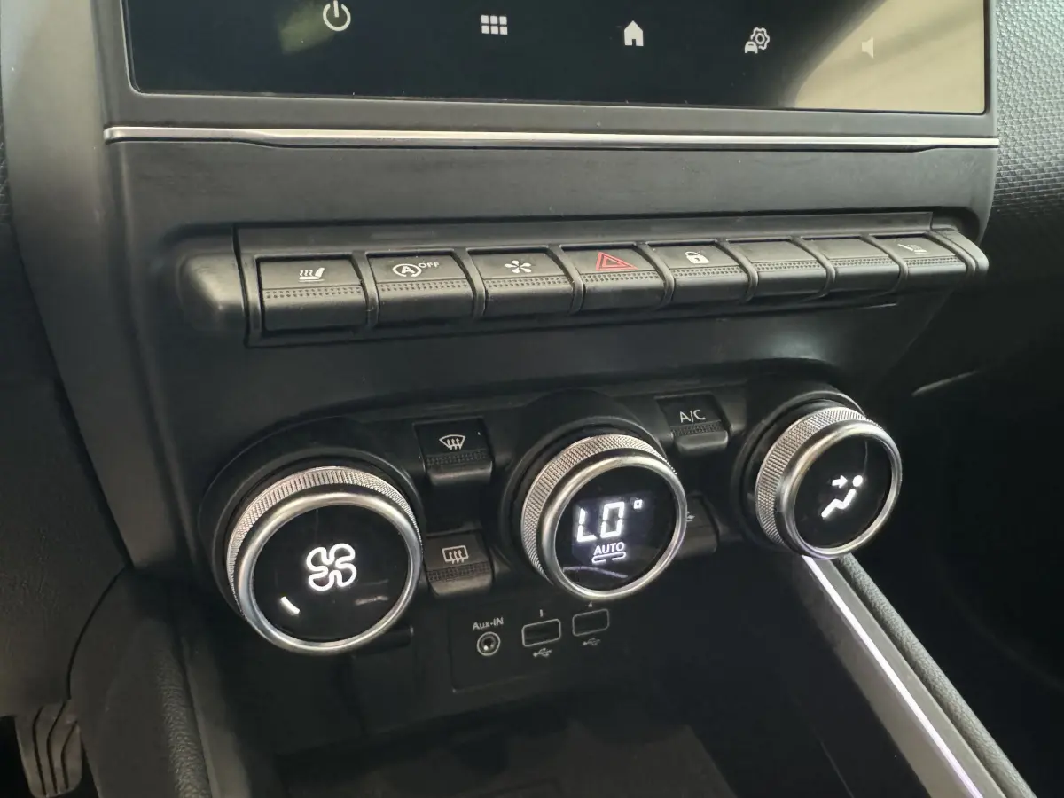 Gros plan sur la console centrale noire de la Renault Clio Intens 2020, montrant les commandes de climatisation et boutons multifonctions.