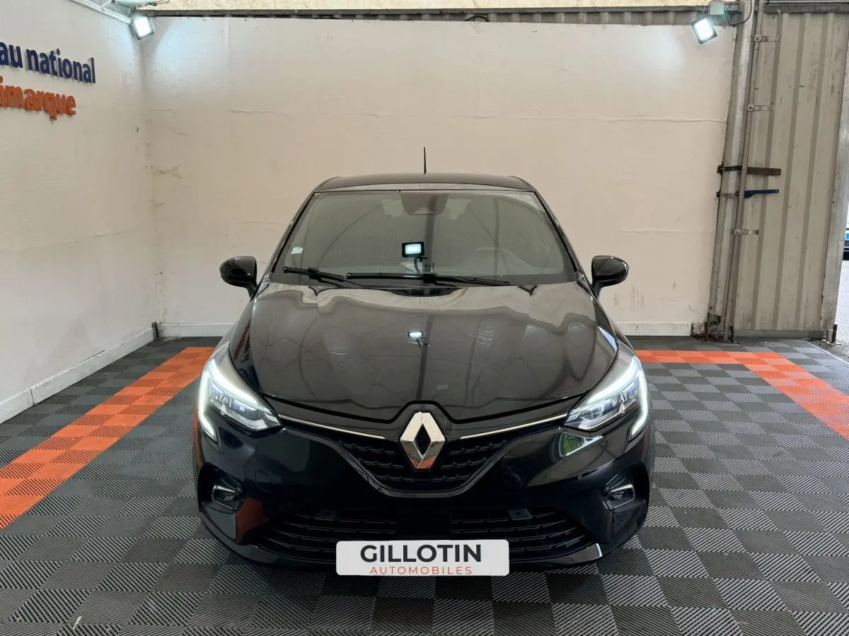 Vue avant d'une Renault Clio Intens TCe 100 noire avec phares LED allumés dans un showroom.