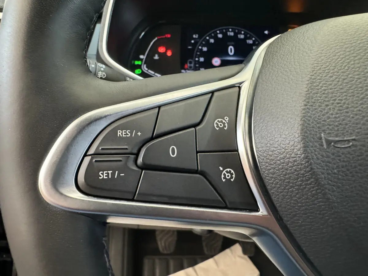 Gros plan sur les commandes du régulateur de vitesse au volant cuir noir de la Renault Clio Intens TCe 100 2020.