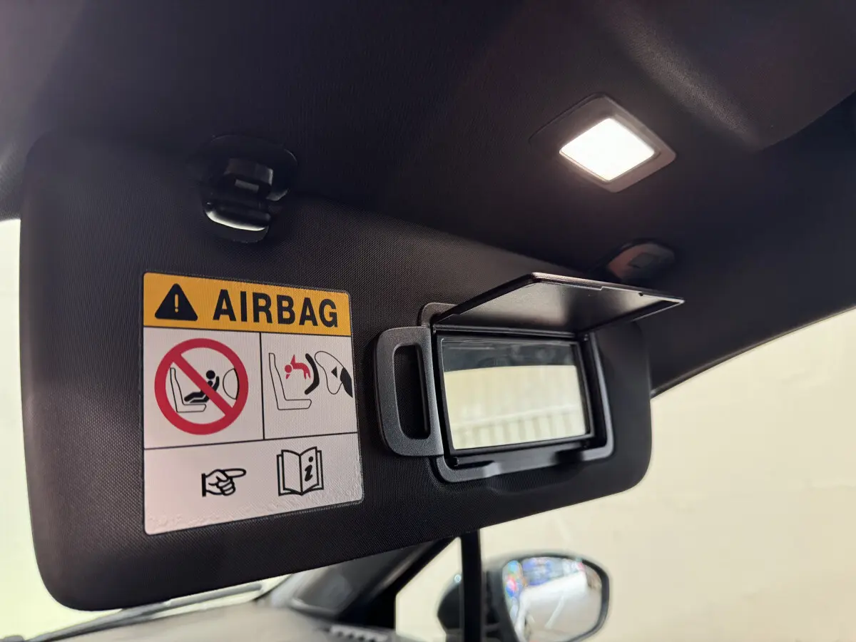 Détail du pare-soleil côté conducteur avec miroir ouvert et avertissement airbag dans Renault Clio Intens noir 2020.