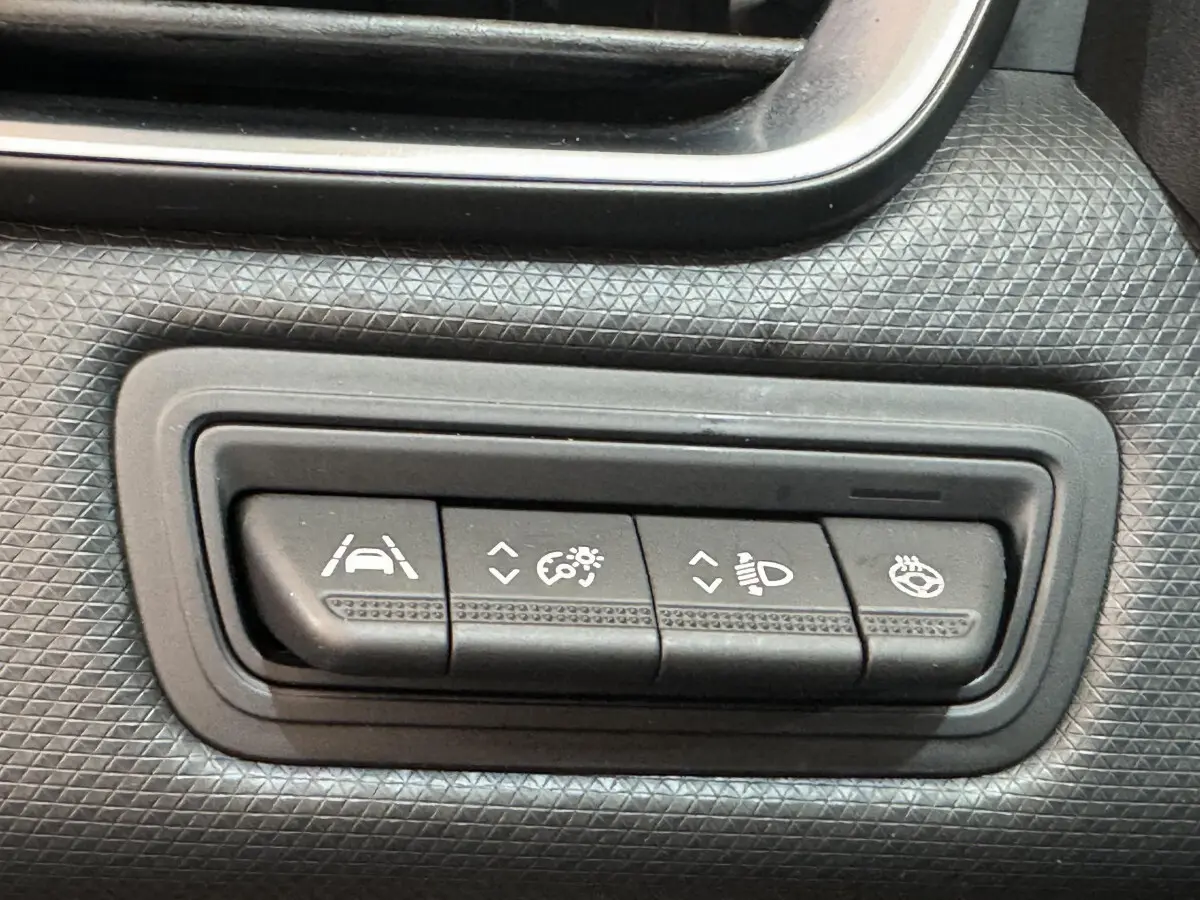 Boutons de réglage d'aide à la conduite et éclairage sur tableau de bord noir texturé d'une Renault Clio Intens 2020.