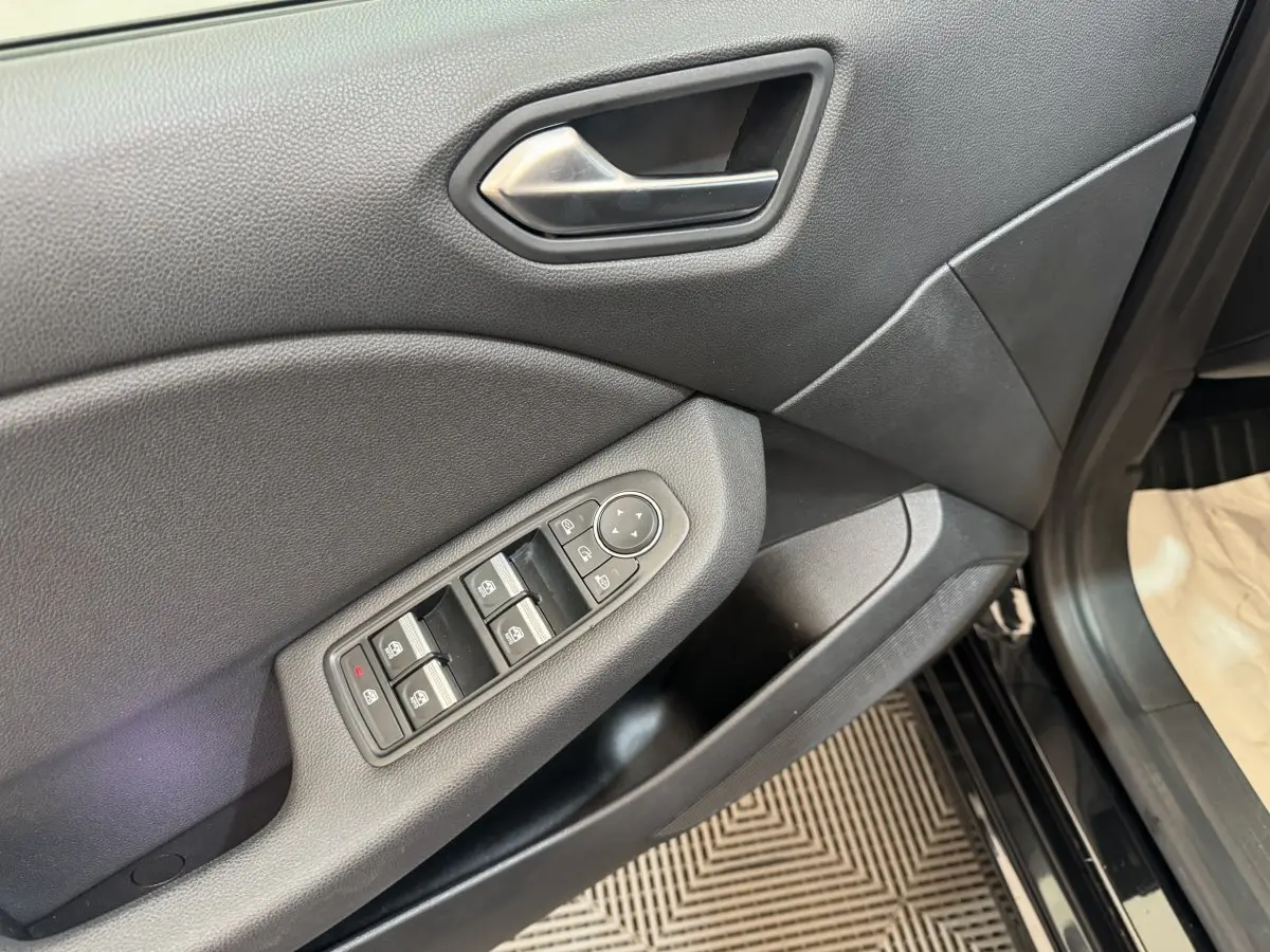 Gros plan sur la porte côté conducteur de la Renault Clio Intens TCe 100 noire, montrant les commandes des vitres électriques.