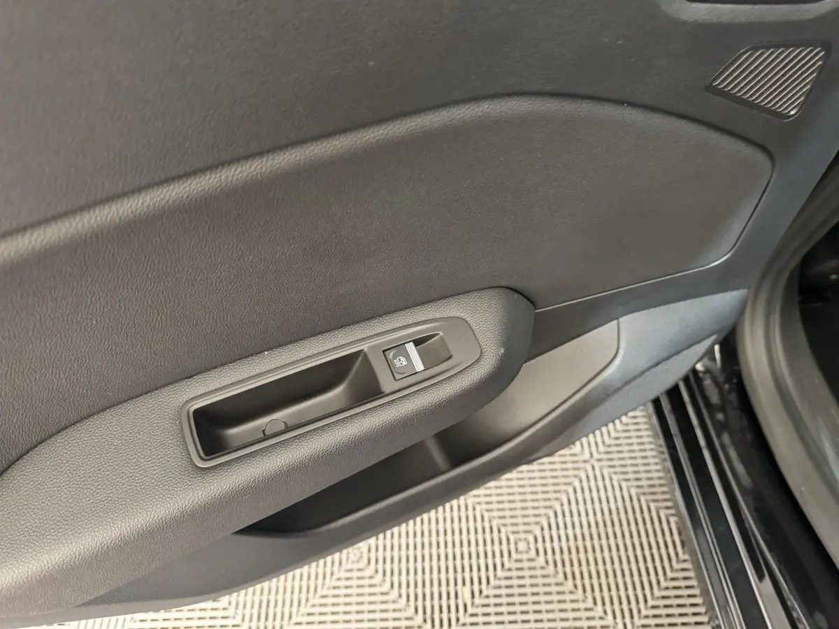 Gros plan sur la poignée intérieure de la porte côté conducteur d'une Renault Clio Intens TCe 100 noire de 2020.