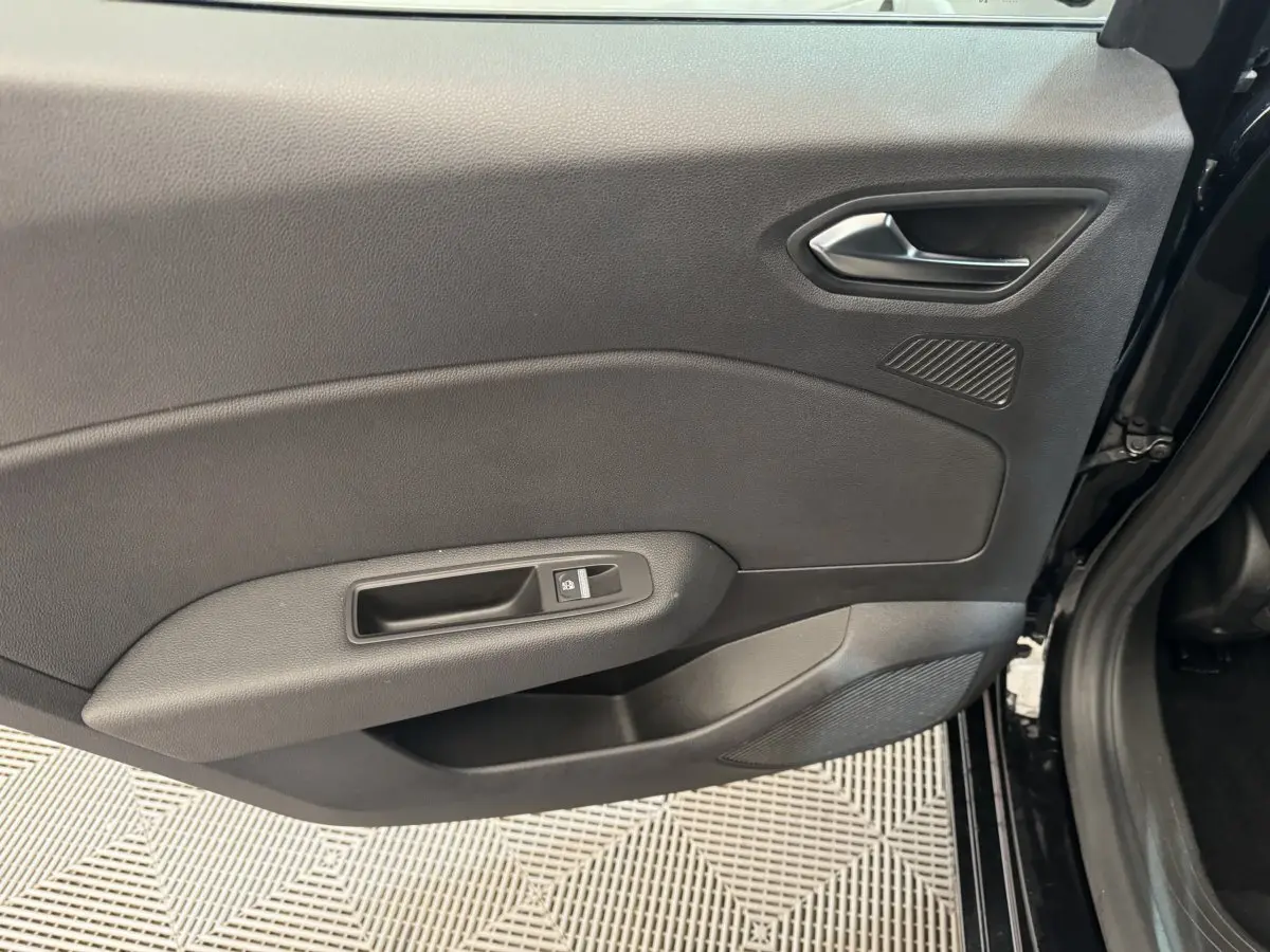 Vue rapprochée de la porte intérieure côté droit noire de la Renault Clio Intens TCe 100, avec poignée et commande de lève-vitre.