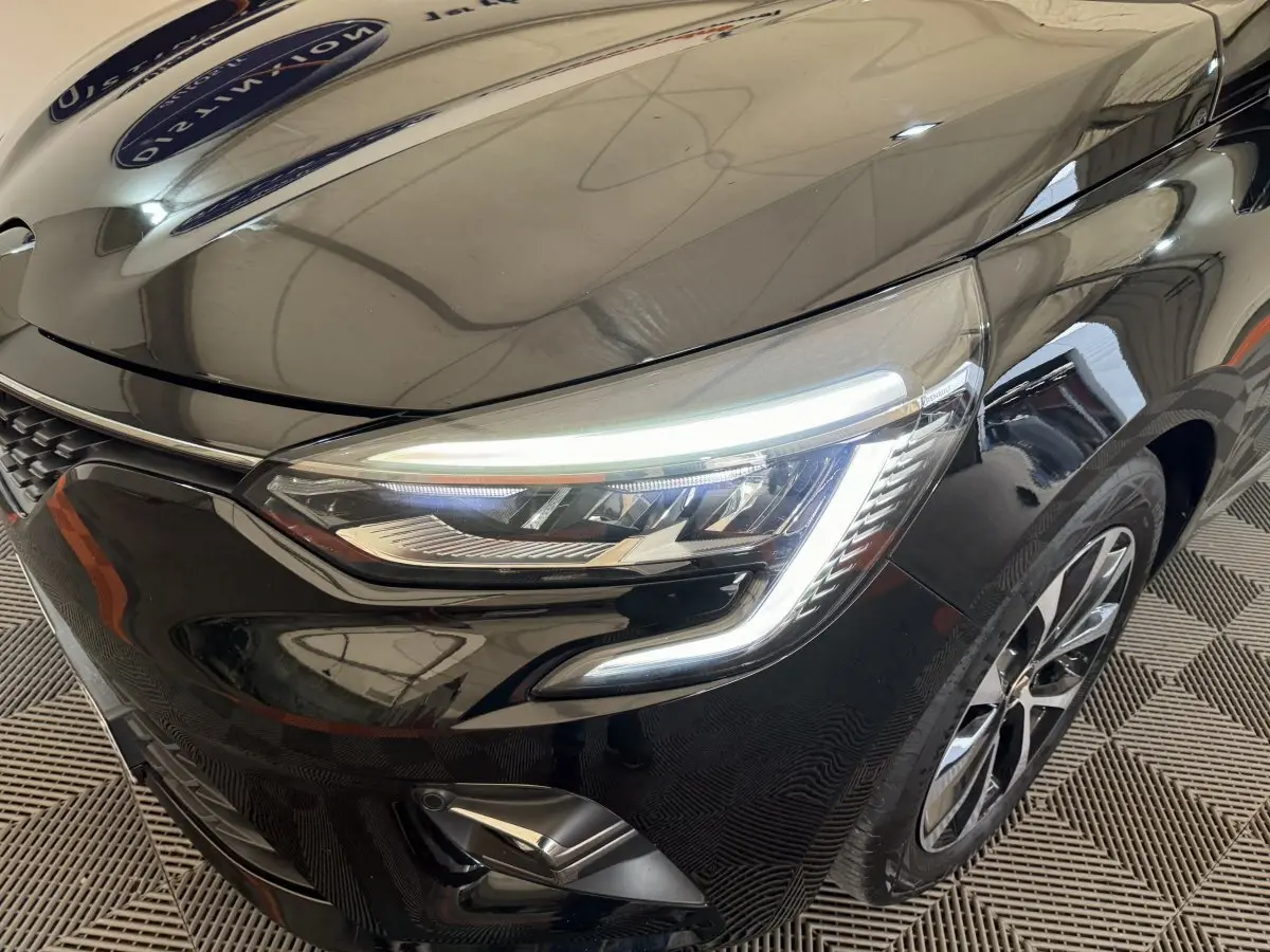 Gros plan sur l'avant droit de la Renault Clio Intens TCe 100 noire, mettant en valeur ses phares LED et jante alliage.