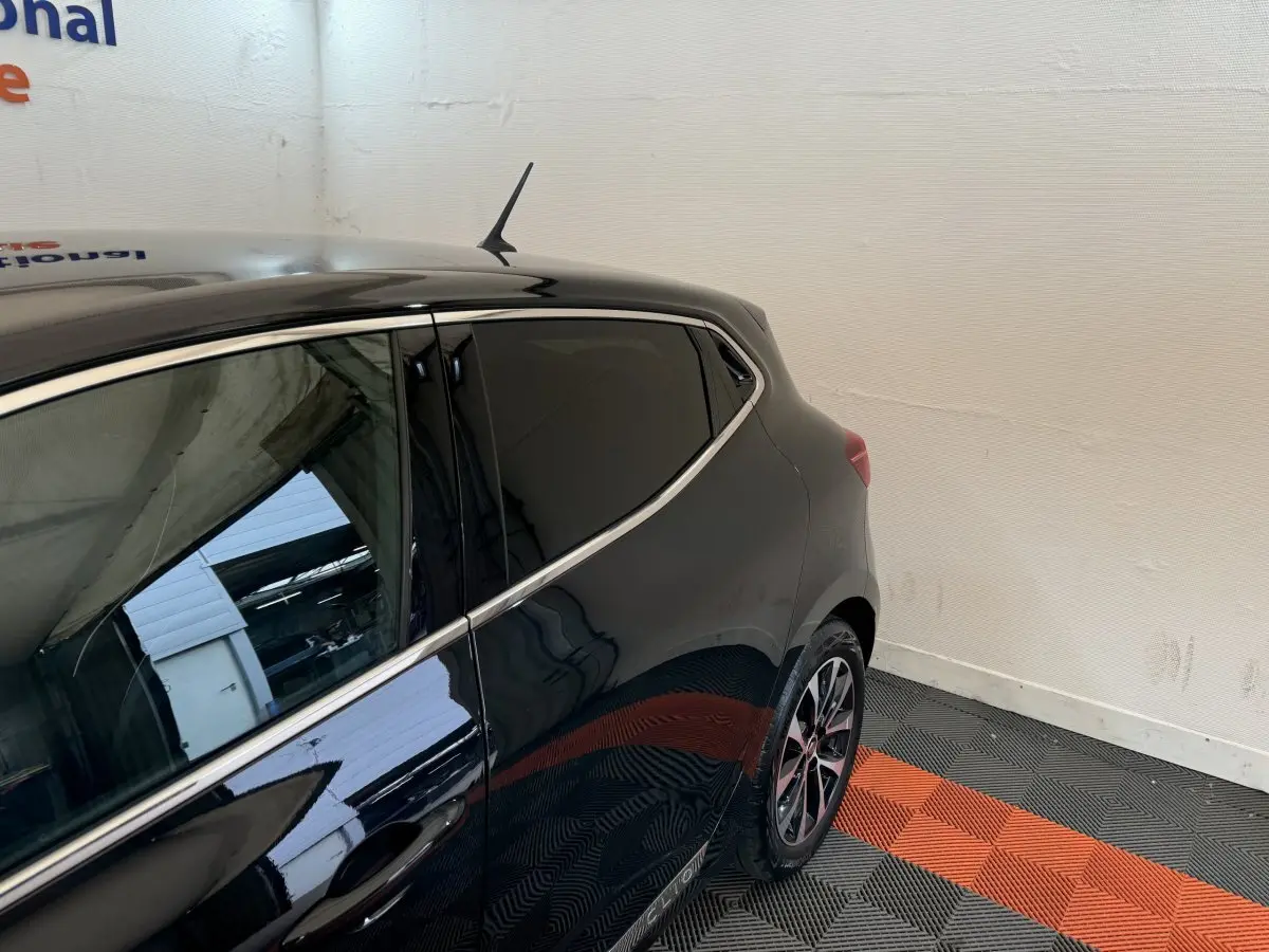 Vue arrière côté gauche d'une Renault Clio Intens TCe 100 noire avec vitres teintées et jantes alliage.