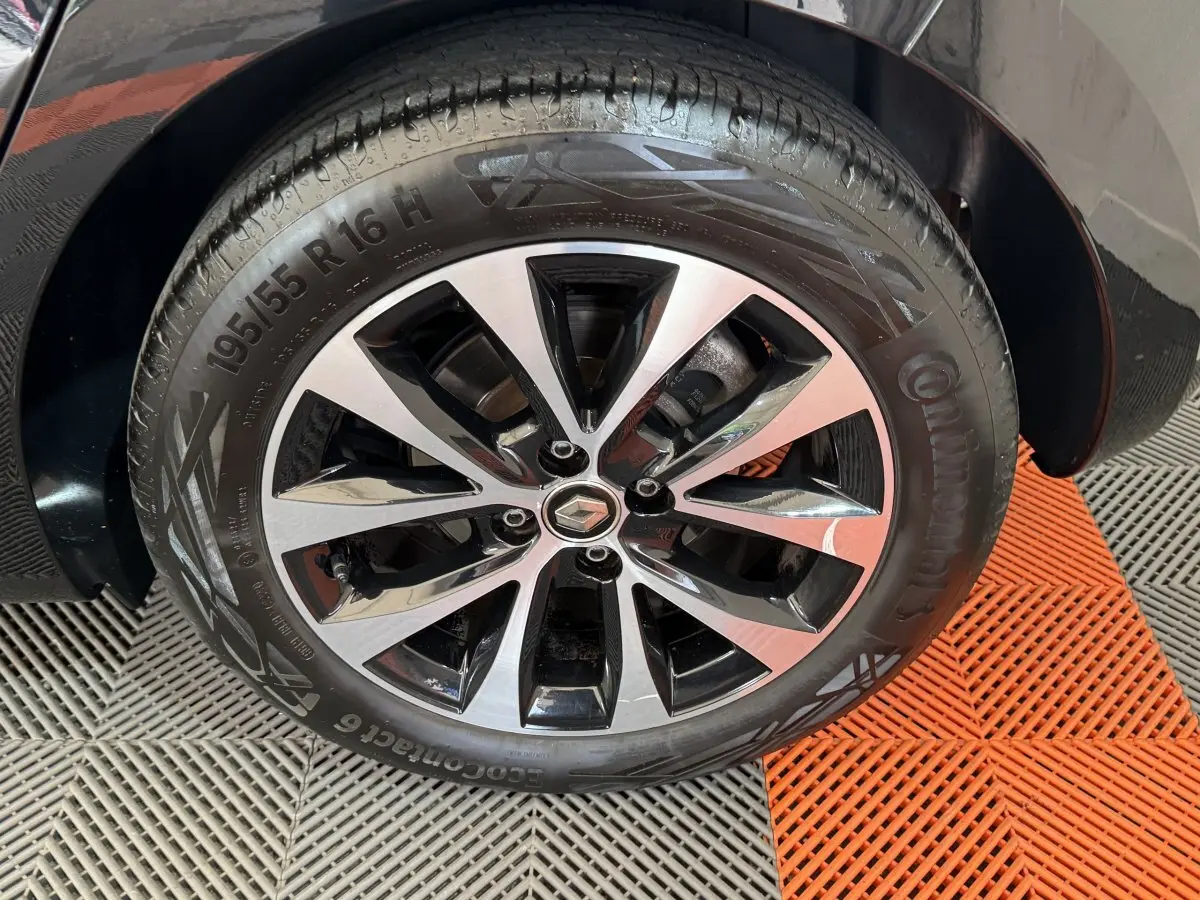 Gros plan sur la roue avant droite noire d'une Renault Clio Intens TCe 100 avec jante alliage bicolore.