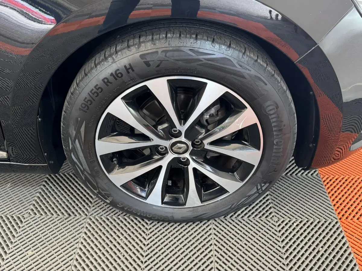 Gros plan sur la roue avant gauche noire de la Renault Clio Intens TCe 100 avec jante alliage bicolore.