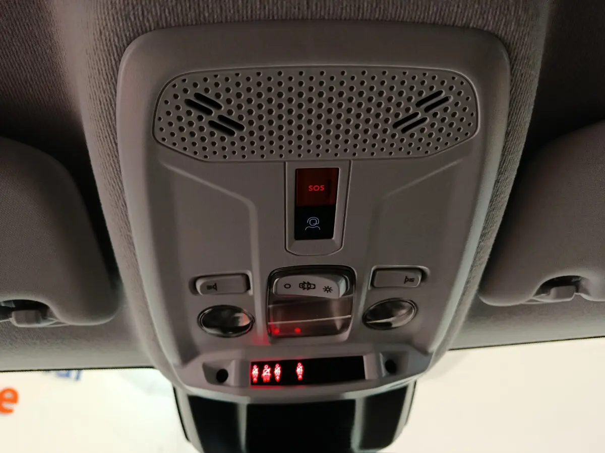 Vue en contre-plongée du panneau de commande de plafond intérieur gris clair avec bouton SOS rouge et éclairages intégrés Peugeot 208 PureTech 2025