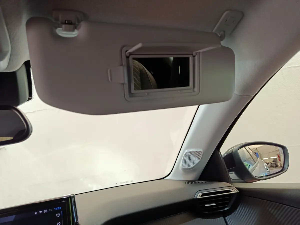 Détail intérieur du pare-soleil avec miroir ouvert et rétroviseur droit visible dans une Peugeot 208 gris clair.