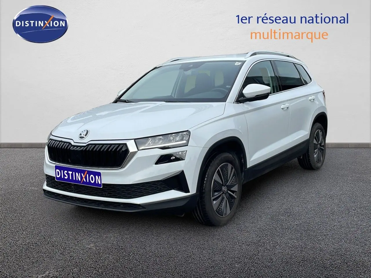 Vue 3/4 avant droite du Skoda Karoq blanc glacier 2025 avec calandre noire et jantes bi-ton.