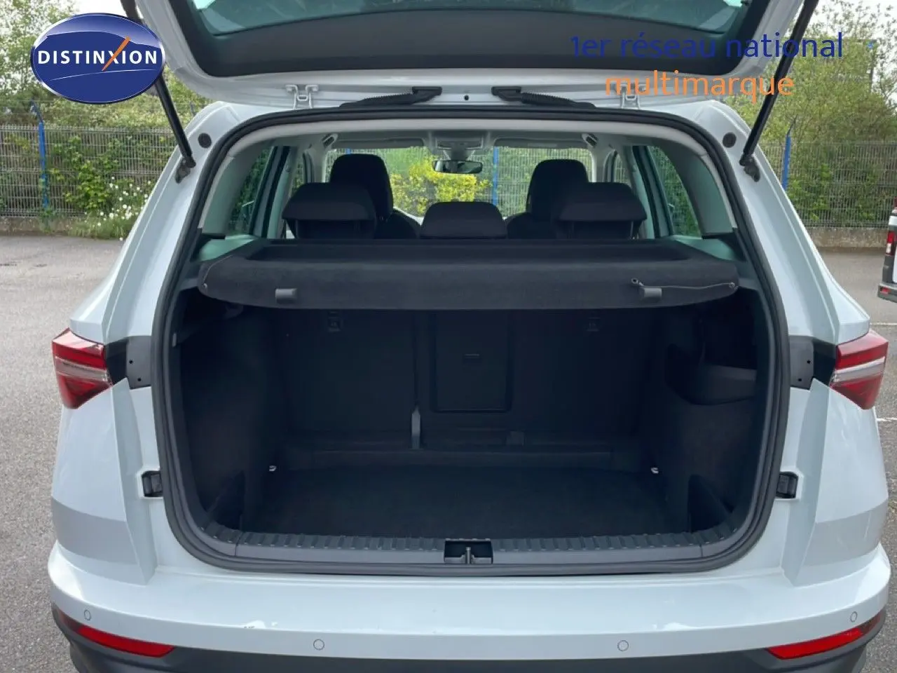 Vue arrière ouverte du coffre du Skoda Karoq blanc glacier 2025, mettant en valeur l'espace de chargement vide.