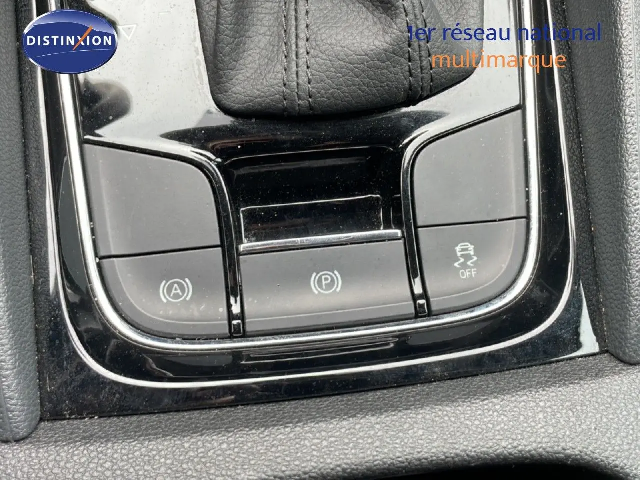 Gros plan sur la console centrale noire brillante du Skoda Karoq blanc glacier, montrant les boutons de contrôle électroniques.